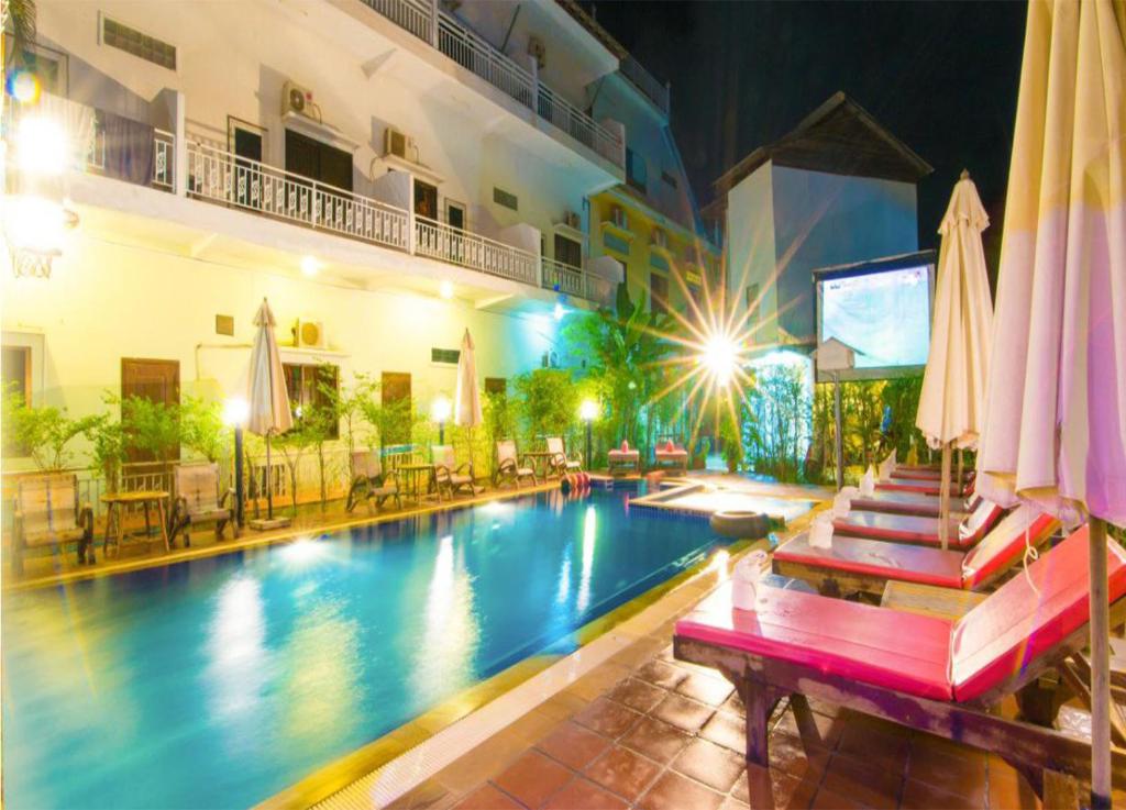 a swimming pool with tables and umbrellas next to a hotel at Blossoming Romduol Boutique in Siem Reap
