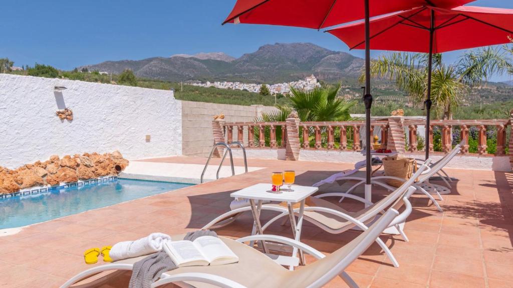 un patio avec des chaises et des parasols à côté d'une piscine dans l'établissement Villa Sol Alozaina by Ruralidays, à Alozaina