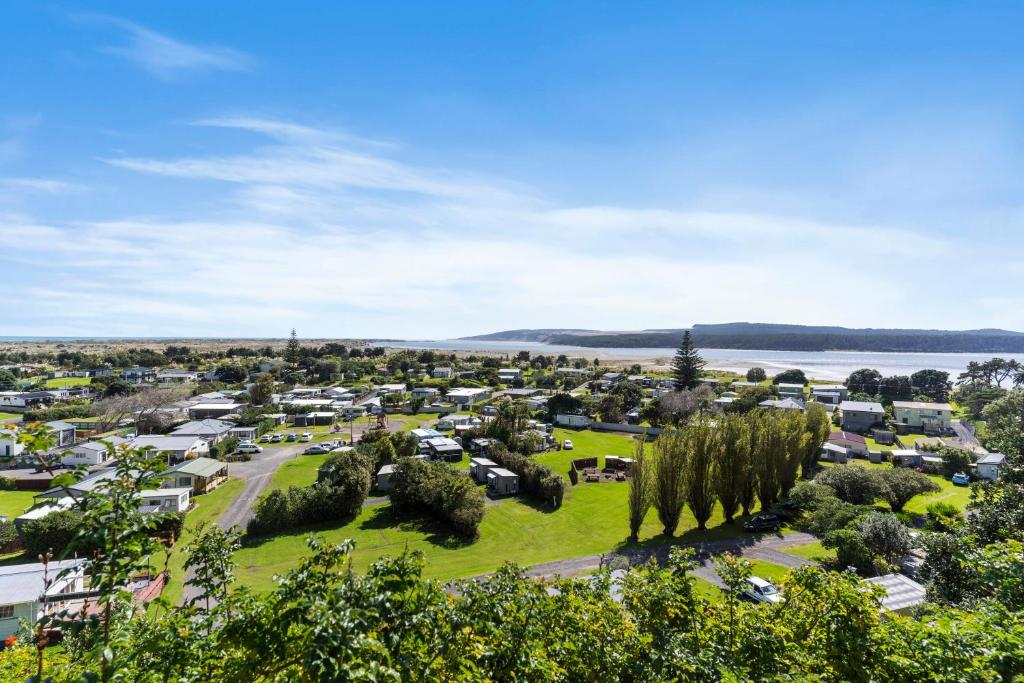 an aerial view of a caravan park with trees and a lake at Port Waikato Holiday Park in Port Waikato