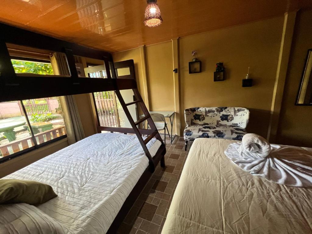 a bedroom with two bunk beds and a chair at Tortuguero Hill Rooms in Tortuguero