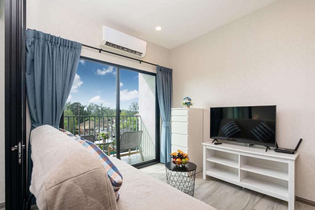 a bedroom with a bed and a tv and a balcony at The Title Residencies Nai Yang - 1 Bedroom Apartment in Nai Yang Beach