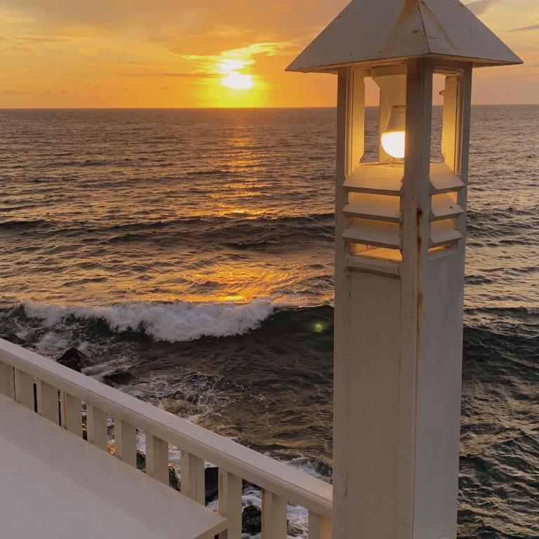 einen Leuchtturm auf einem Balkon mit Blick auf den Sonnenuntergang im Meer in der Unterkunft Wailanga Resort in Ternate