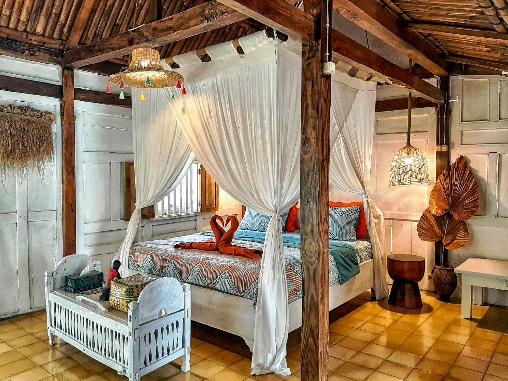 sypialnia z łóżkiem z baldachimem i zasłonami w obiekcie Janur Bungalow w mieście Borobudur