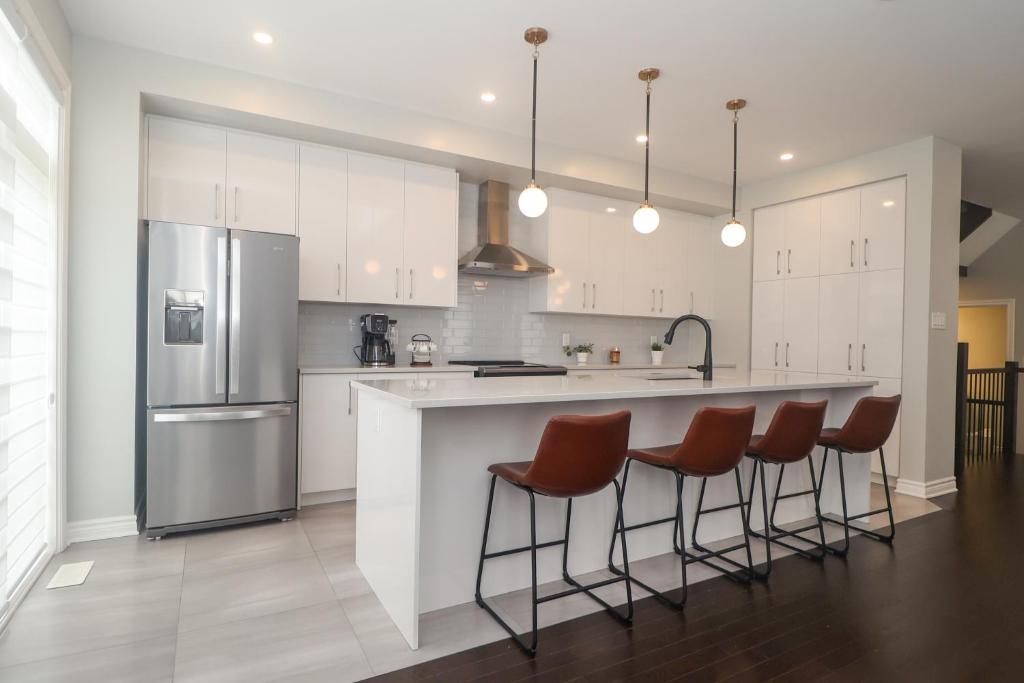 a kitchen with white cabinets and a island with bar stools at Tranquil Nest By The Airport in Ottawa