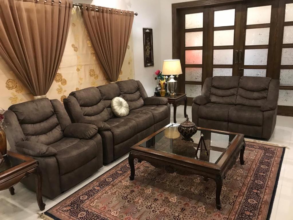 - un salon avec un canapé et une table basse dans l'établissement MJS Entire New Designer House, 5 BR, 13 bed, 2 living, reclining sofas, Italian kitchen, 6 bath, garage, side garden at prime location of Bahria Town, Islamabad, à Rawalpindi