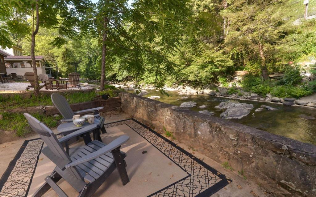 two chairs and a table on a patio next to a stream at On River Time in Gatlinburg