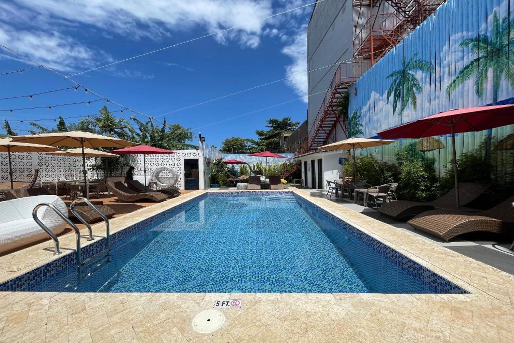 una piscina con sedie e ombrelloni accanto a un edificio di Attic Capsule Hotel a Marigondon