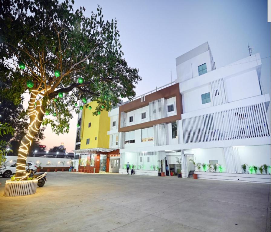 uma árvore no meio de um estacionamento ao lado de um edifício em The Sky Land Hotel & Restaurant em Tuljapur