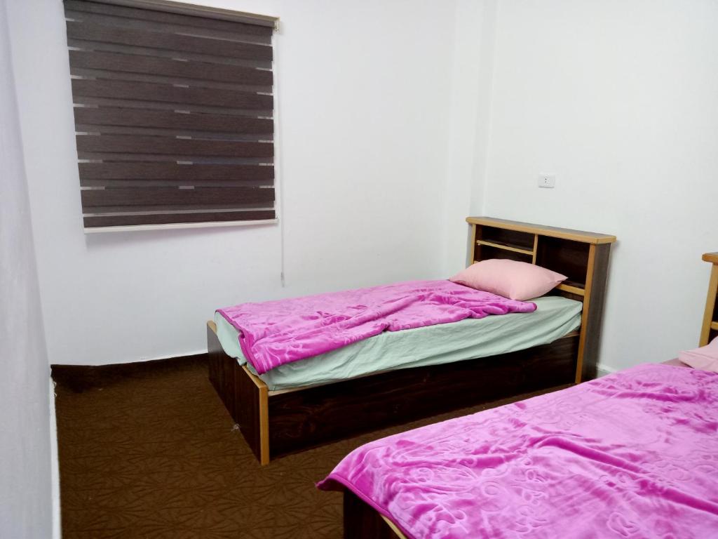 um quarto com 2 camas e uma janela com lençóis roxos em رأس منيف /عجلون em Ajlun
