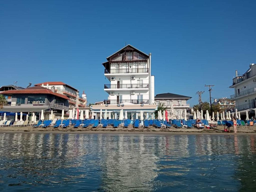 un edificio sulla spiaggia con sedie e acqua di Nepheli a Paralia Katerinis