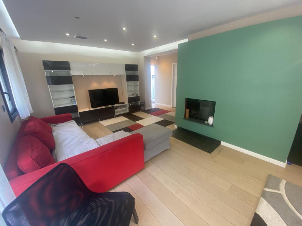 un soggiorno con divano rosso e TV di La Frontonnaise - Villa d'architecte Nord Toulouse a Saint-Sauveur