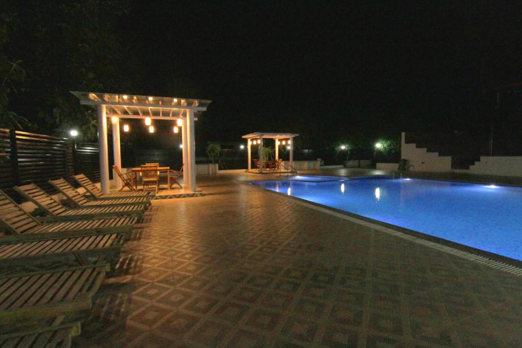 una piscina por la noche con sillas y cenador en Reva Resorts and Holiday Homes, en Chittoor