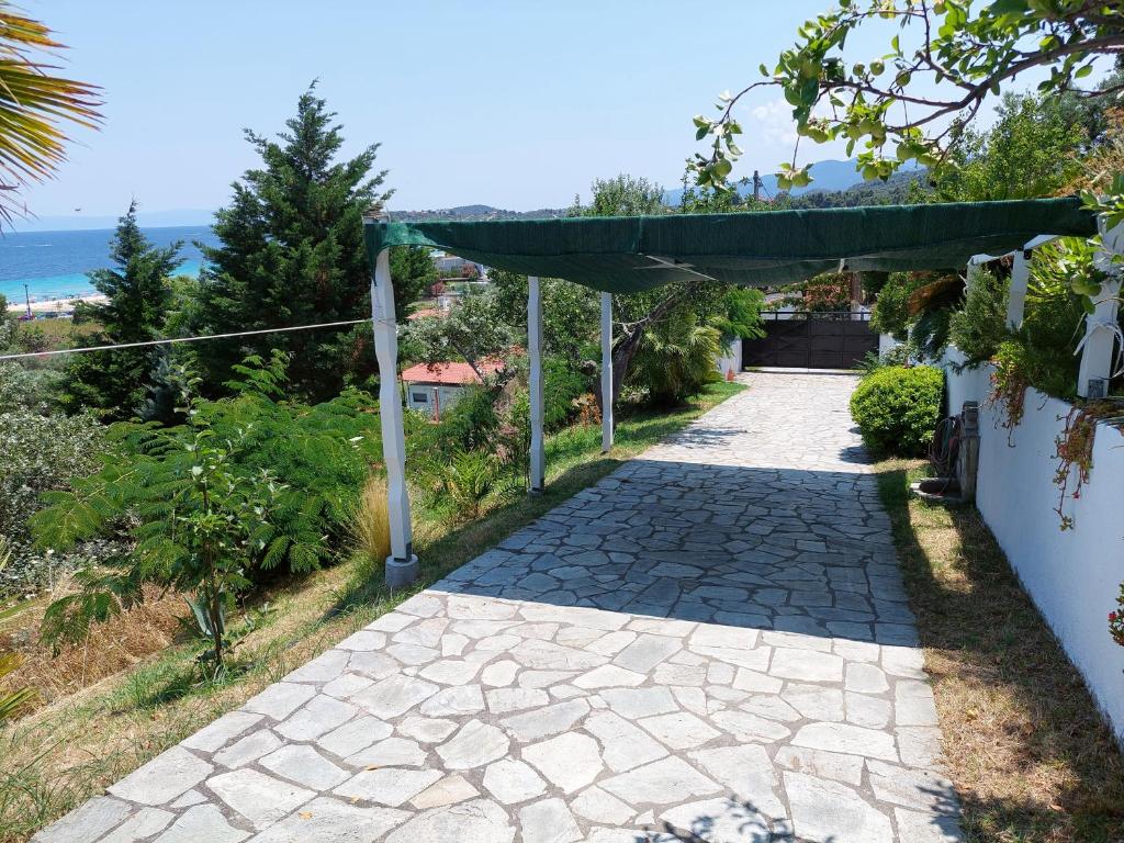 a stone walkway with a green pergola at Seaview dreams in Ormos Panagias