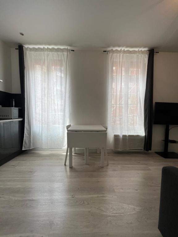 une chambre avec une table devant deux fenêtres dans l'établissement Central location near the Sacré-Coeur, à Paris