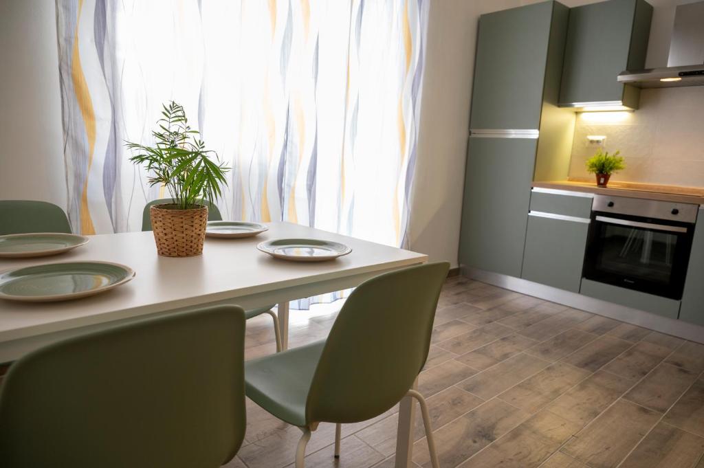 una cucina con tavolo, sedie verdi e finestra di antica dogana apartments maestrale a Terracina