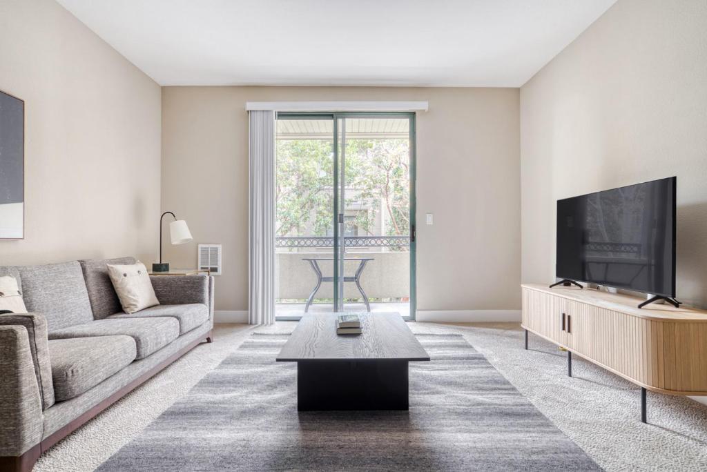 a living room with a couch and a tv at San Mateo 2BR w Pool Gym easy highway access SFO-713 in Foster City
