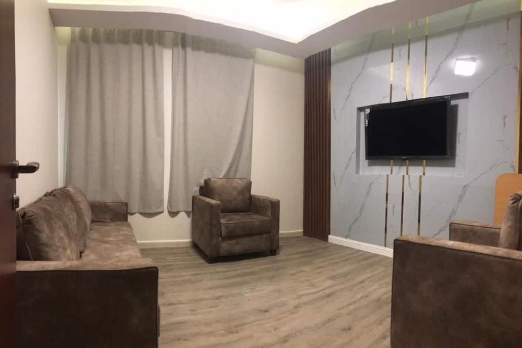 Hayat Al madinah Hotel فندق حياة المدينة في المدينة المنورة: غرفة معيشة مع كرسيين وتلفزيون بشاشة مسطحة