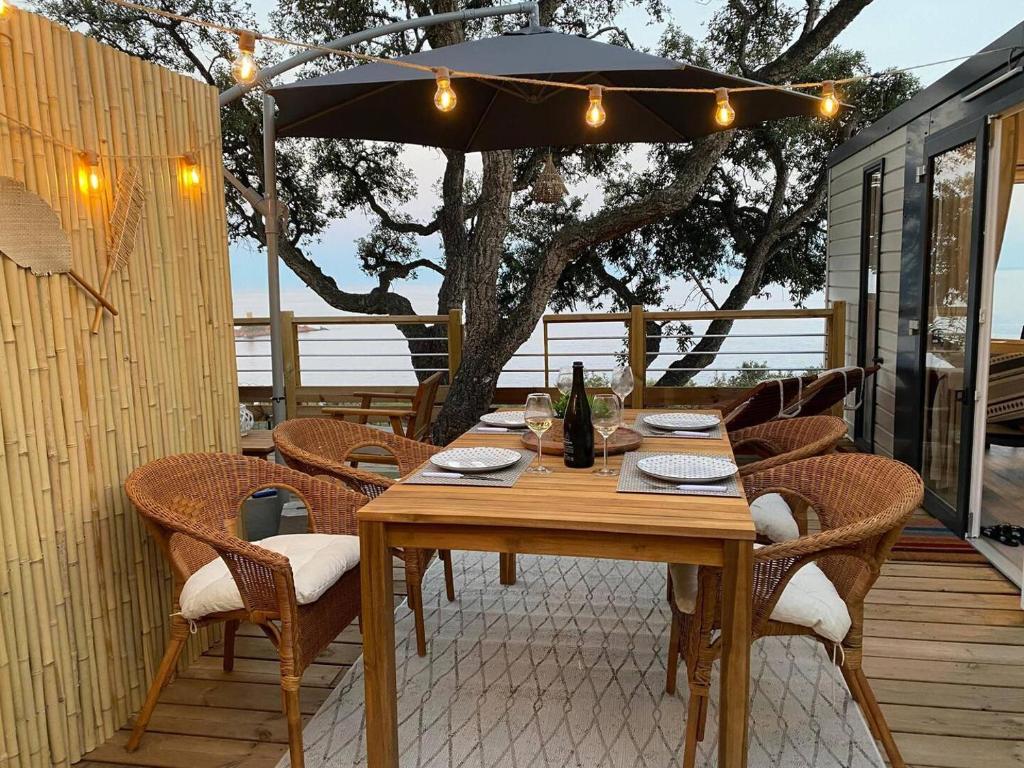 a wooden table with chairs and an umbrella on a deck at L&#39;arbre perché in Saint-Raphaël