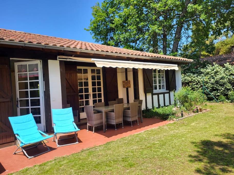 a patio with chairs and a table in front of a house at Fermette Landaise près de l'Océan et du lac marin in Vieux-Boucau-les-Bains