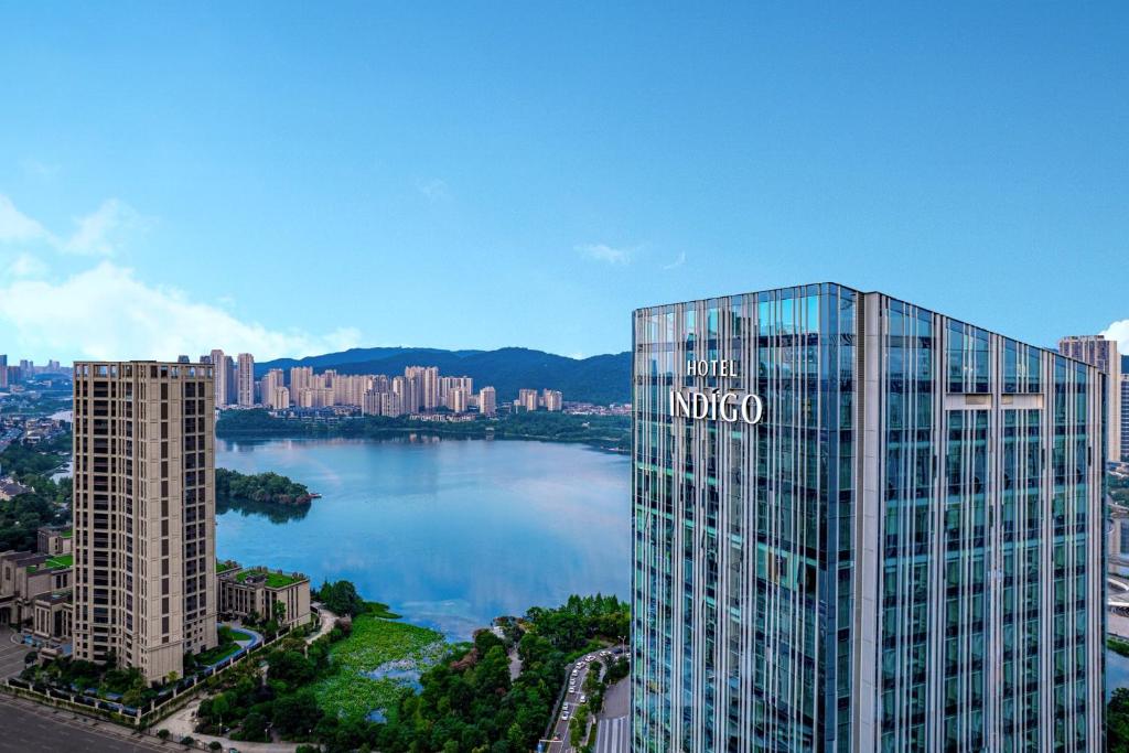 Blick auf ein großes Glasgebäude neben einem See in der Unterkunft Hotel Indigo Changsha Meixi Lake in Changsha