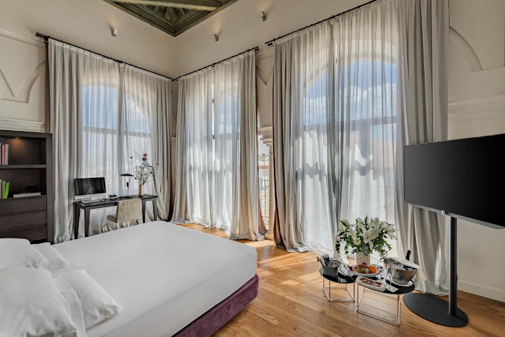 a bedroom with a large bed and large windows at CoolRooms Palacio Villapanés 5 GL in Seville