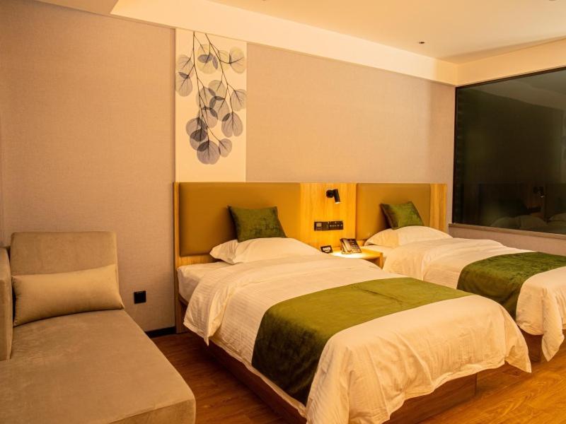 a hotel room with two beds and a chair at GreenTree Inn Express Hotel Fuyang Development Zone Oriental Pearl in Fuyang
