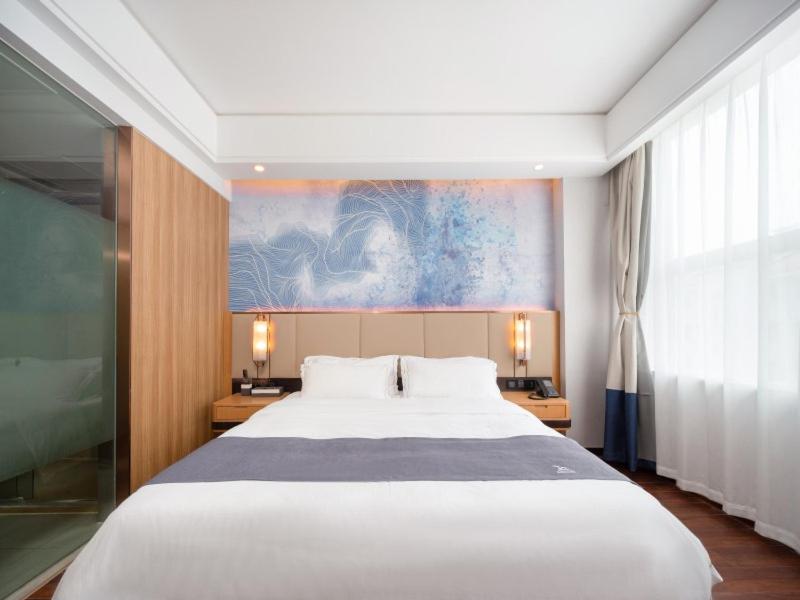 a bedroom with a large white bed and a painting at GreenTree Eastern Hotel Lihu Yuantouzhu Scenic Area in Wuxi