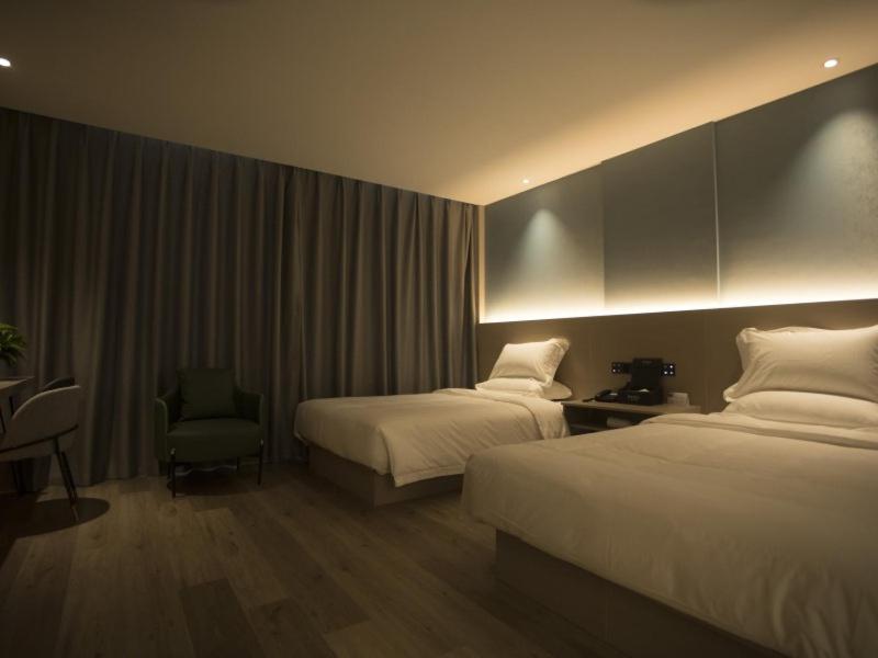 a hotel room with two beds and a chair at Geli Hotel Suqian Shuyang Yingbin Avenue in Shuyang