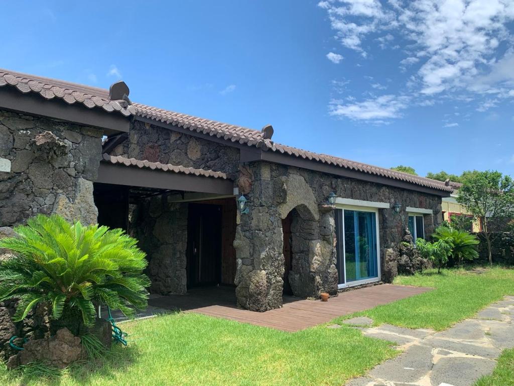 a stone house with a porch and a patio at Bijarim Healing Pension in Jeju