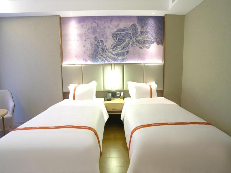 two beds in a hotel room with a painting on the wall at GreenTree Eastern Hotel Xuzhou Pei County Binhe Road in Pei