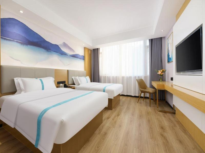 a hotel room with two beds and a flat screen tv at VX Hotel Dalian Zhoushuizi Airport in Dalian