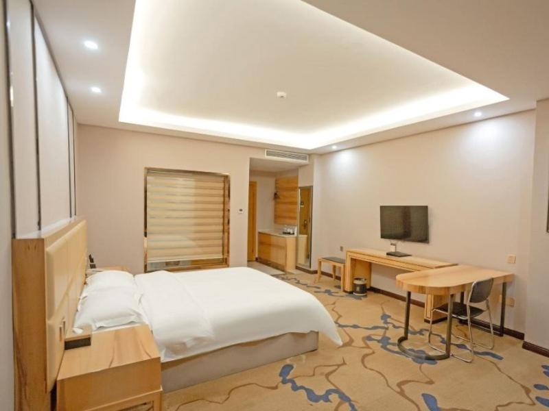 宜春的住宿－格菲宜春市袁州区政府高铁站酒店，一间卧室配有一张床、一张书桌和一台电视
