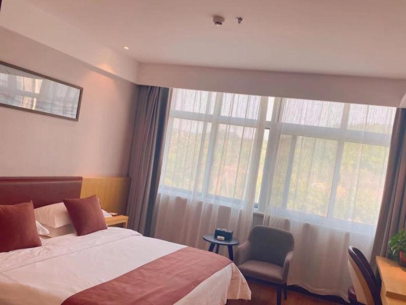 een slaapkamer met een bed en een groot raam bij Geli Hotel Zaozhuang High-Speed Railway Station in Taozhuang