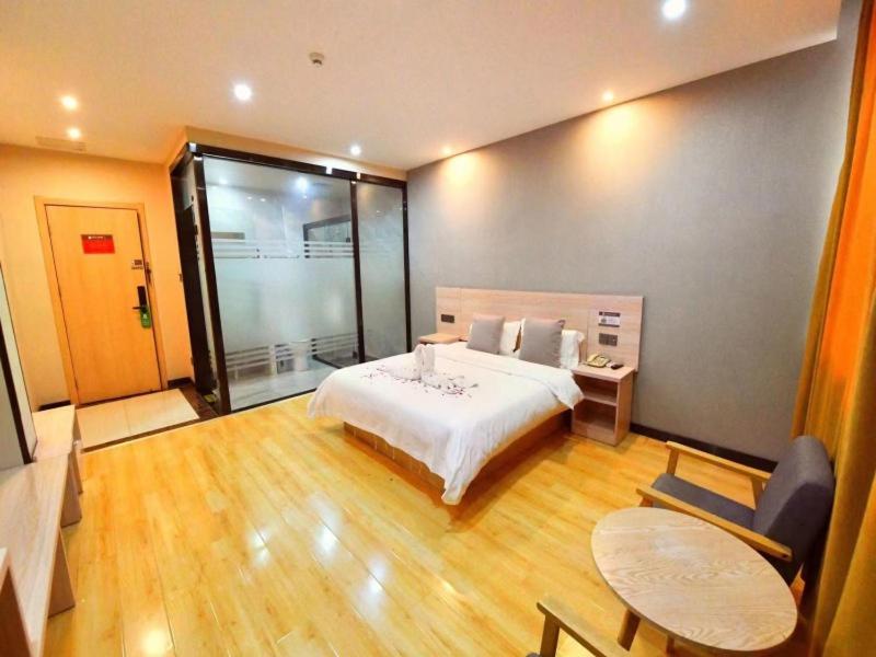 Un dormitorio con una gran cama blanca y una mesa en Geli Hotel Xuzhou Government Olympic Sports Center, en Xuzhou