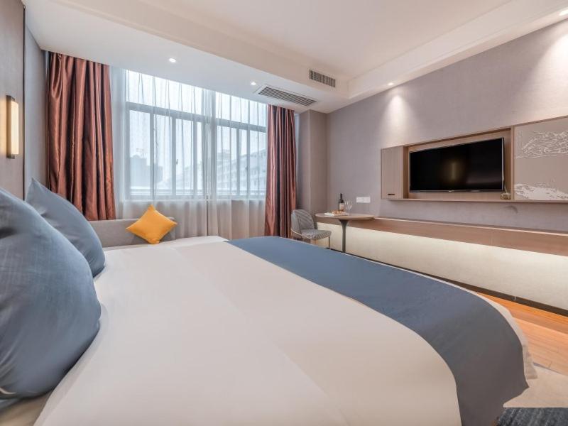 GreenTree Inn Yulin Hongjin Markey Yide في Yulin: غرفة فندقية بسرير كبير وتلفزيون بشاشة مسطحة