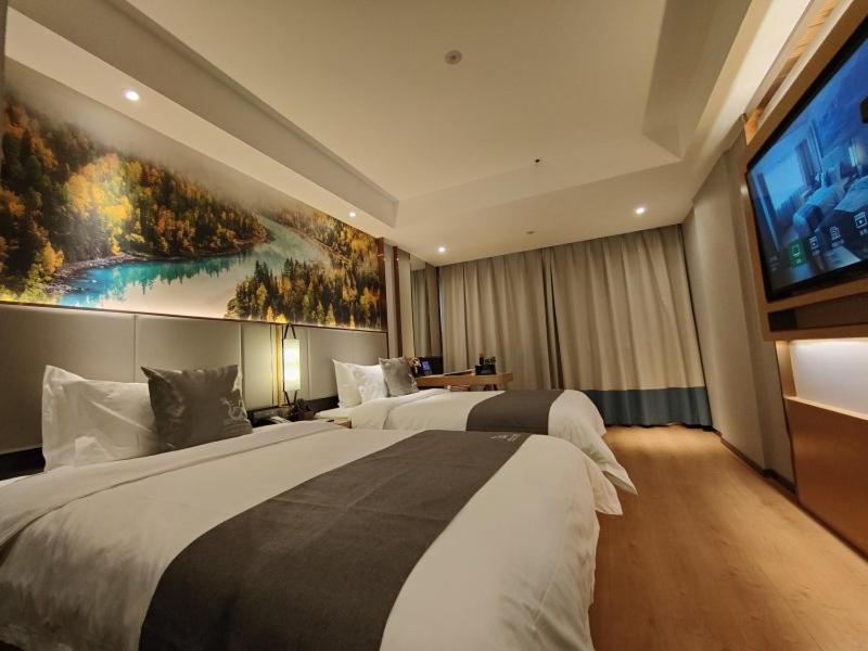 a hotel room with two beds and a flat screen tv at GreenTree Eastern Hotel Xinjiang Urumqi Renmin Road in Ürümqi