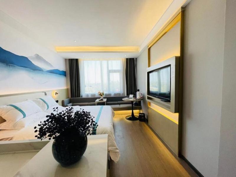 a hotel room with a bed and a vase of flowers at VX Hotel Xiao County Railway Station Century Avenue zheshang Market in Mengzhuang