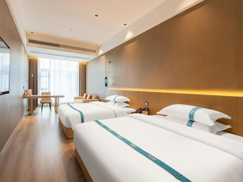 a hotel room with three beds and a table at VX Hotel Xuzhou Suining Remin Road in Suining