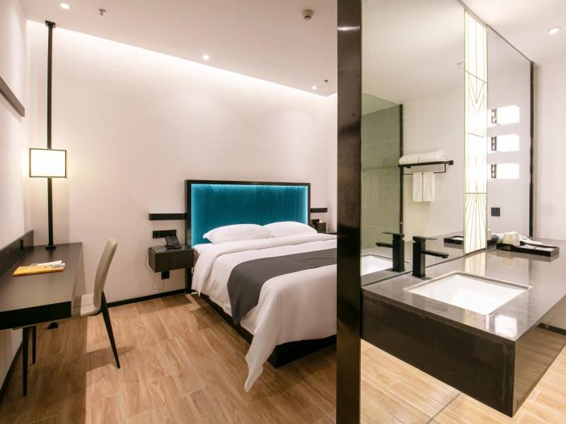 a bedroom with a large bed and a mirror at Geli Hotel Nanning East Railway Station in Nanning