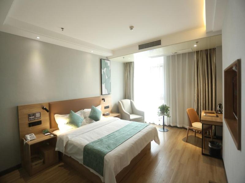 a hotel room with a large bed and a desk at GreenTree Inn Anqing East Yingbin Road High-Speed Railway Station in Anqing