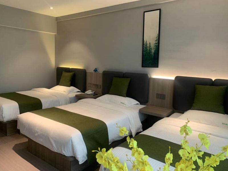 a hotel room with three beds and a picture on the wall at GreenTree Inn Express Hotel Nantong Tongzhou Shigang Town in Tongzhou