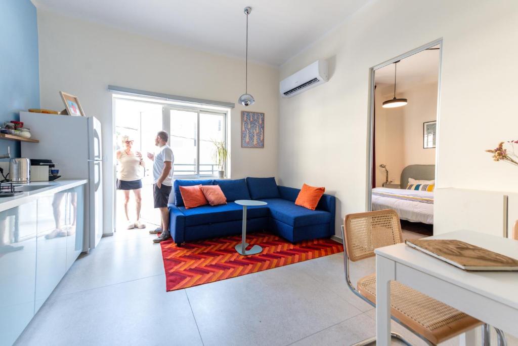 un uomo e una donna in piedi in un soggiorno con un divano blu di My TLV City suite a Tel Aviv