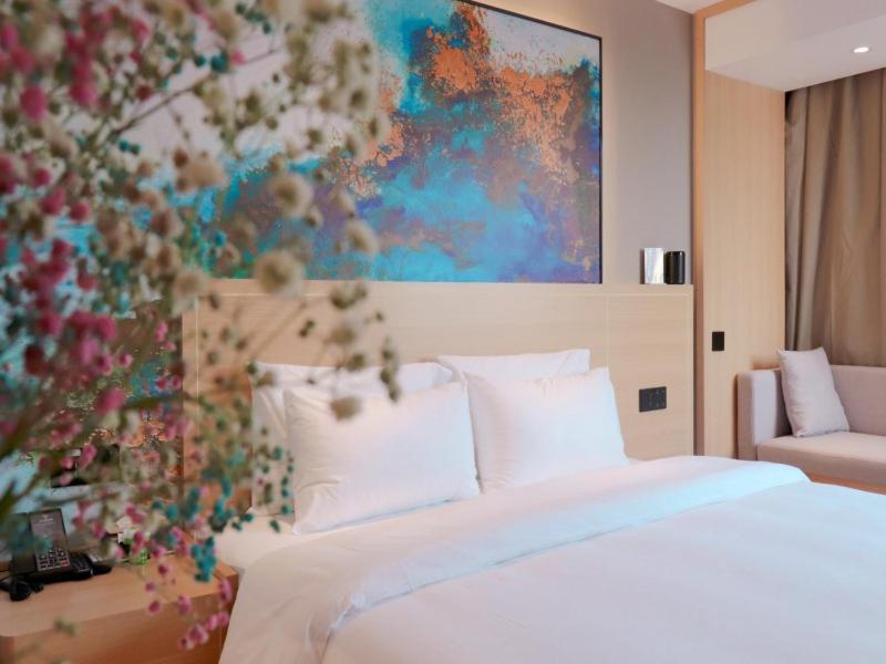 - une chambre avec un lit et une peinture murale dans l'établissement VX Hotel Fuyang Railway Station East Beijing Road, à Fuyang