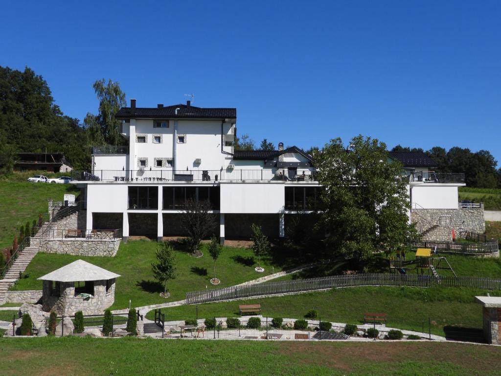 un grand bâtiment blanc au-dessus d'un champ verdoyant dans l'établissement MOTEL ALADIN, à Cazin