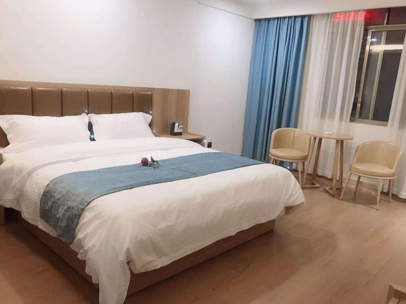 1 dormitorio con 1 cama grande, mesa y sillas en GreenTree Inn Guangdong Zhanjiang Donghai Island, en Zhanjiang