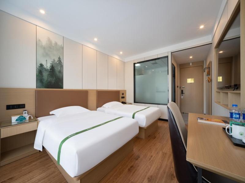 a hotel room with two beds and a desk and a desk at GreenTree Inn Express Hotel Suzhou Taicang West Nanjing Road in Taicang