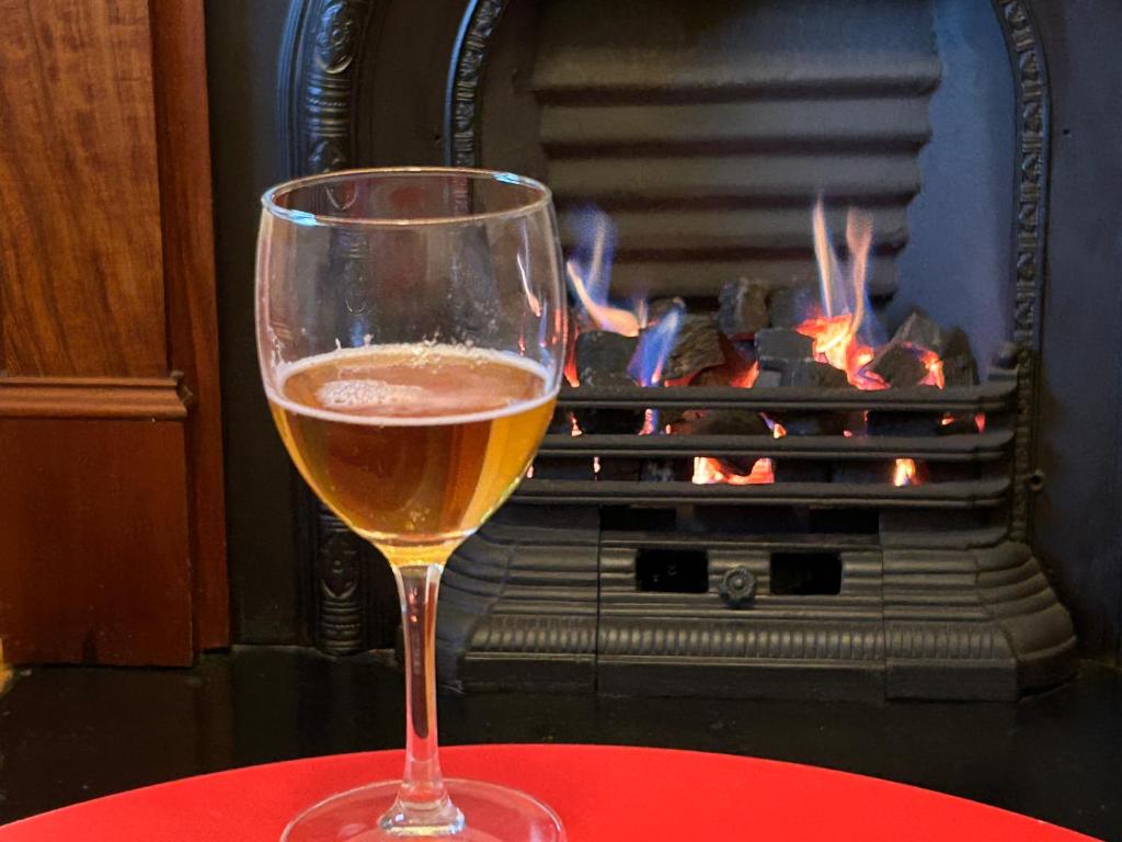a glass of wine sitting on a table in front of a fireplace at Charm on Carrington in Adelaide