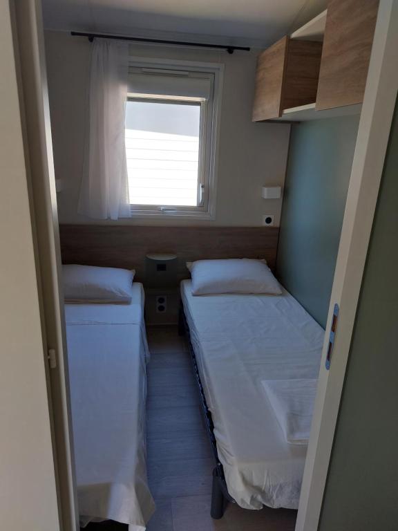 two beds in a small room with a window at L&#39;arbre perché in Saint-Raphaël
