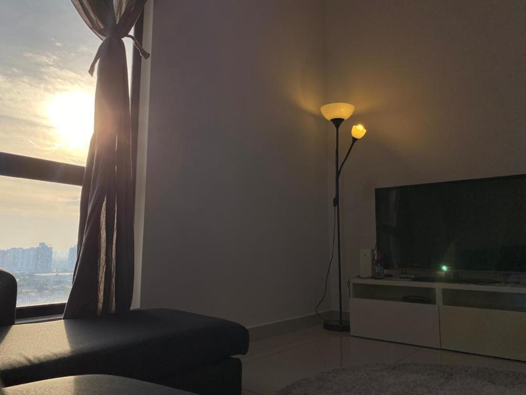 ein Wohnzimmer mit einem TV und einem Fenster in der Unterkunft Islamic Santai Santai Homestay - Centrus Soho Cyberjaya in Cyberjaya