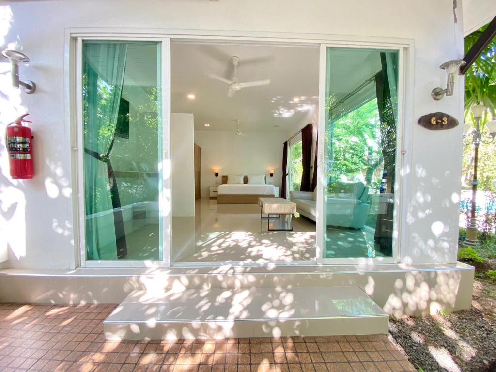 a glass house with a living room and a bedroom at Garden Home Kata in Kata Beach